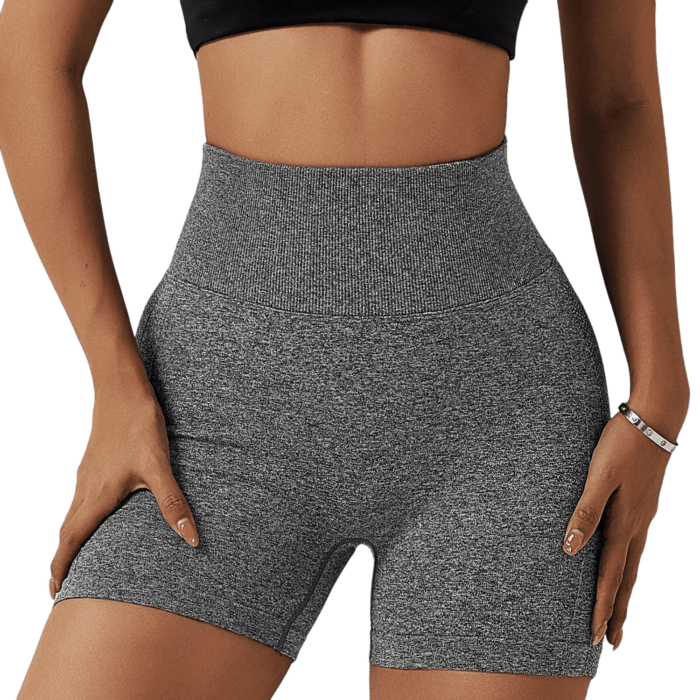 Person in chic athletic wear: grey shorts, black crop top, hands on hips.